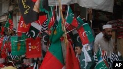 Flags of political parties are on sale ahead of elections, in Peshawar, Pakistan, Friday, July 20, 2018. 