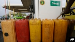 FILE - A man fills containers with diesel at a petrol station in Abuja, Nigeria, May 26, 2015. The new government of President Muhammadu Buhari said it would get country’s four refineries back up and running.