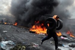 A demonstrator holds tires as he runs during a protest against Ecuador's President Lenin Moreno's austerity measures in Quito, Ecuador October 12, 2019.