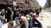 FILE - Residents wait to receive food aid distributed by the U.N. refugee agency at the Palestinian refugee camp of Yarmouk, south of Damascus, Syria, May 2014.