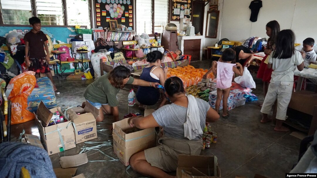 A family packs relief foods sent by relatives at a school building turned into an evacuation center in Loboc town, Bohol province on Dec. 21, 2021, days after super Typhoon Rai devastated the province. 