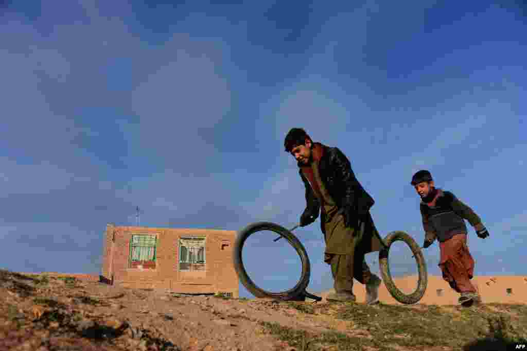 Afghan boys play with tyres along a street on the outskirts of Herat.