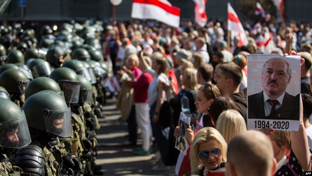 Belarusian security forces block a street during an opposition rally challenging official presidential elections results, in Minsk, Belarus, Aug. 30, 2020. The poster depicts President Alexander Lukashenko and the years he has been in power.