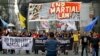 A policeman takes a picture of activists as they march to mark the second year of martial law in Mindanao, during a rally near the Malacanang palace in Manila, Philippines on Friday, May 24, 2019.