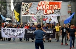 A policeman takes a picture of activists as they march to mark the second year of martial law in Mindanao, during a rally near the Malacanang palace in Manila, Philippines on Friday, May 24, 2019.