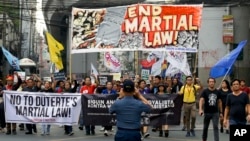 A policeman takes a picture of activists as they march to mark the second year of martial law in Mindanao, during a rally near the Malacanang palace in Manila, Philippines on Friday, May 24, 2019.
